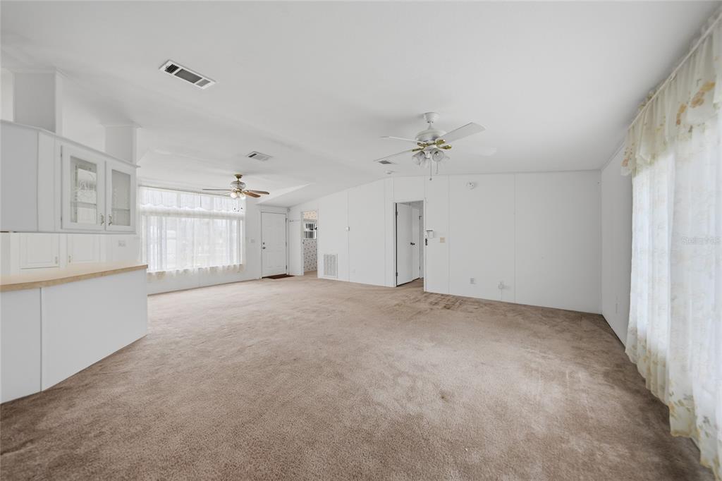 A spacious, carpeted living room features white walls, two ceiling fans, and large windows — 11923 SW LOOP TERRACE, ARCADIA, FL