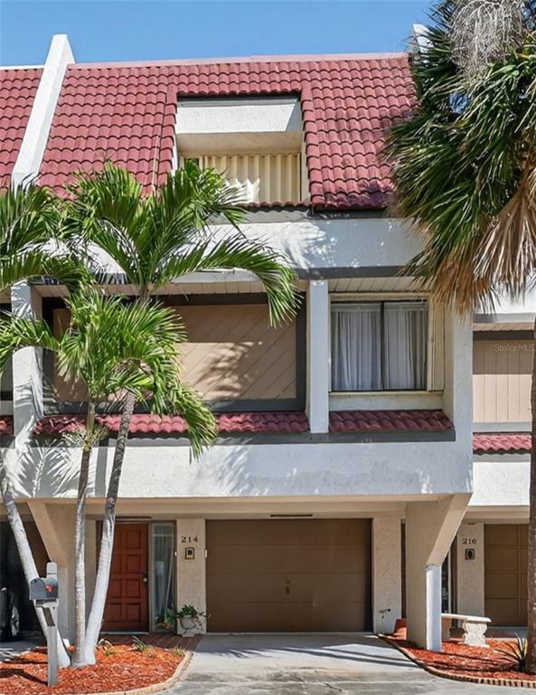 A multi-story townhouse exterior features a red tile roof, a garage, and palm trees — 214 SKIFF POINT UNIT 214, CLEARWATER, FL