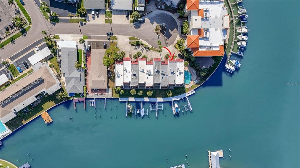 An aerial view shows a row of waterfront townhomes with boat slips and a pool — 214 SKIFF POINT UNIT 214, CLEARWATER, FL