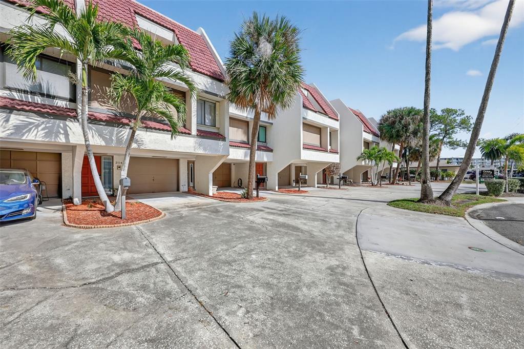 A row of multi-story townhouses with red roofs and attached garages under a blue sky — 214 SKIFF POINT UNIT 214, CLEARWATER, FL