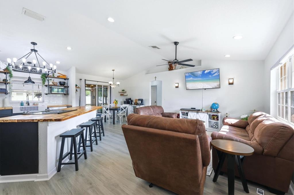 An open-concept living room and kitchen featuring brown leather furniture, a wooden island, and flooring — 2565 CLOVELON STREET, NORTH PORT, FL