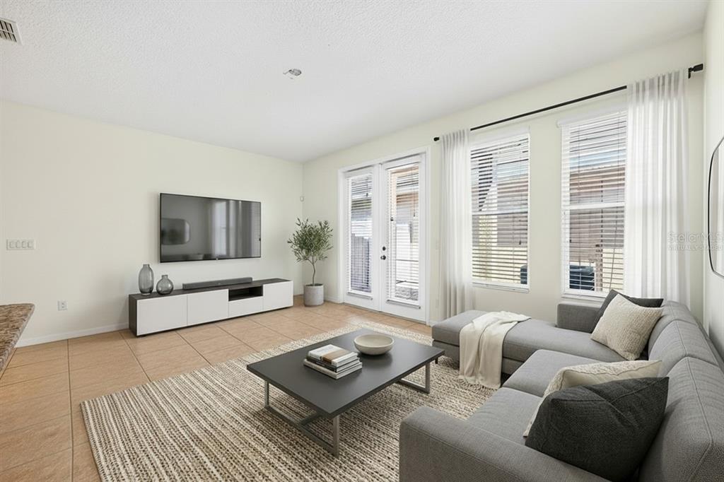 A living room with tile floors, a sectional sofa, a coffee table, and glass doors — 11429 BROWNSTONE STREET, WINDERMERE, FL