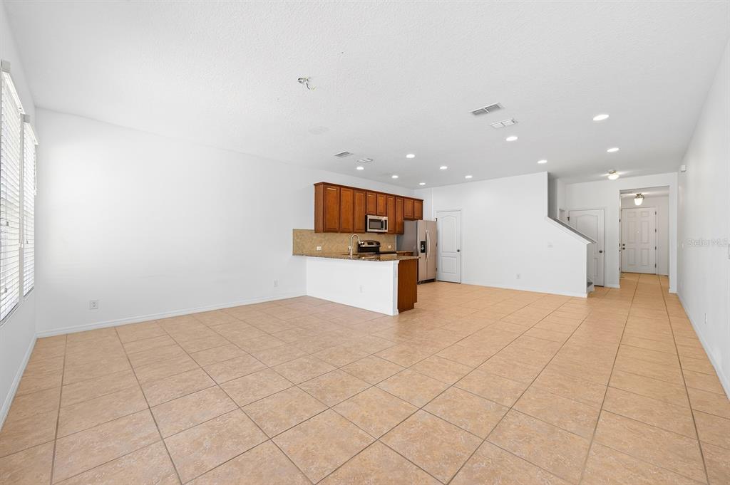 An open-concept kitchen with wood cabinets and tile flooring overlooks a large living area — 11429 BROWNSTONE STREET, WINDERMERE, FL