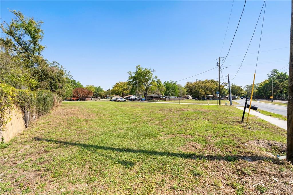 A vacant, grassy lot sits next to a paved road under a clear blue sky — 28 REWIS STREET, OCOEE, FL