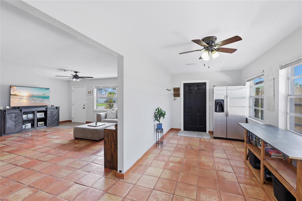 An open-concept living area features terracotta tile flooring, a black front door, and a refrigerator — 3670 SUNSET BEACH DRIVE, VENICE, FL