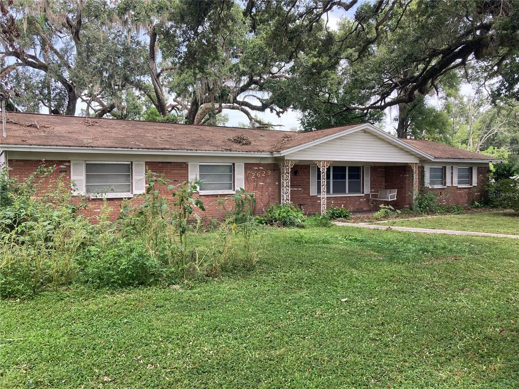 A single-story brick house with a front porch, white trim, and large oak trees — 2629 S PARSONS AVENUE, SEFFNER, FL