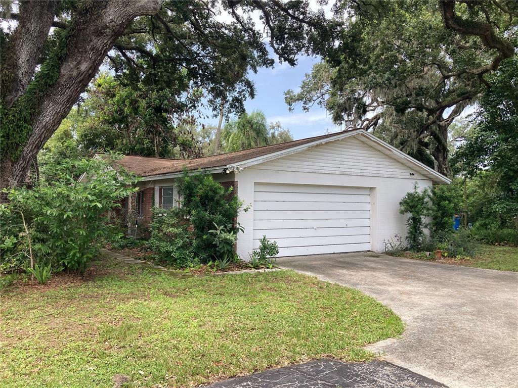 A single-story house with a white garage door, brick accents, and large trees in front — 2629 S PARSONS AVENUE, SEFFNER, FL