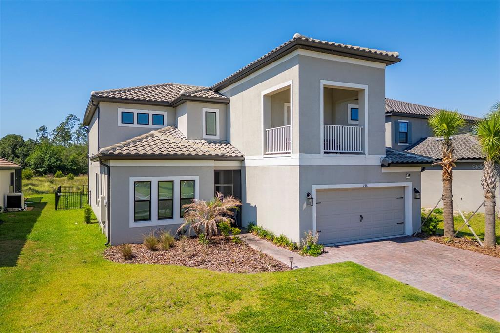 A two-story suburban house with a gray stucco exterior, tile roof, and attached garage — 1951 GOBLET COVE STREET, KISSIMMEE, FL