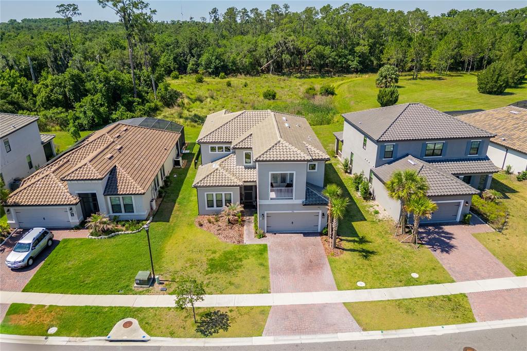 An aerial view shows three suburban houses with tiled roofs and driveways facing a street — 1951 GOBLET COVE STREET, KISSIMMEE, FL