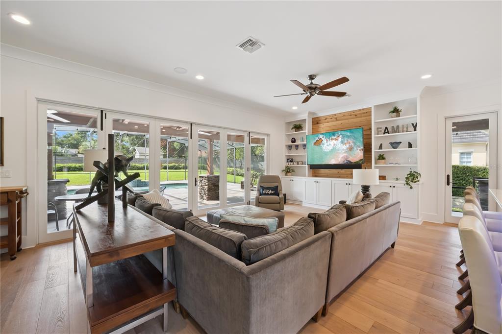 A white kitchen features a large island with bar seating, stainless appliances, and hardwood floors — 11539 LAKE BUTLER BOULEVARD, WINDERMERE, FL