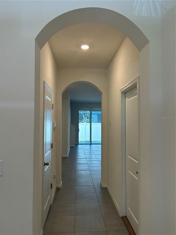 A tiled hallway features arched doorways and white doors leading to a rear sliding glass door — 2913 BELUGA BAY DRIVE, ODESSA, FL