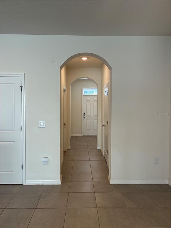 A tiled hallway features arched entryways leading to a white front door with a transom window — 2913 BELUGA BAY DRIVE, ODESSA, FL