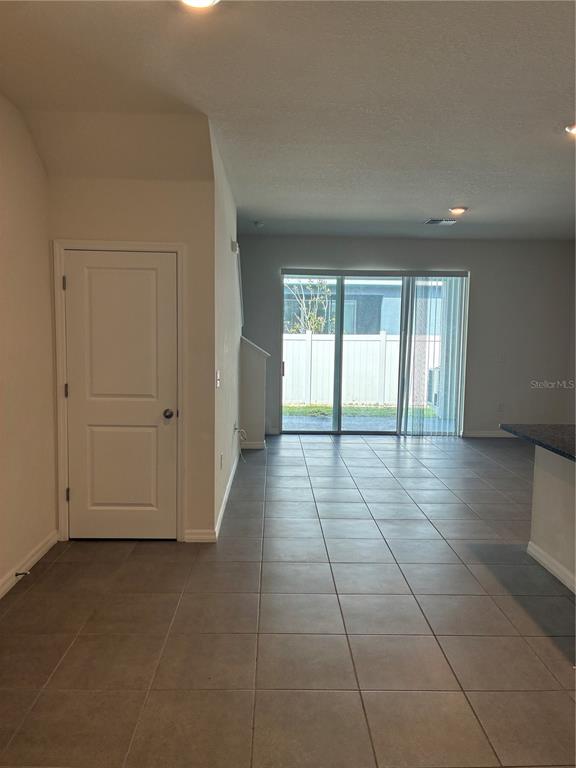 A room with tile flooring, a closed white door, and a sliding glass door to outside — 2913 BELUGA BAY DRIVE, ODESSA, FL
