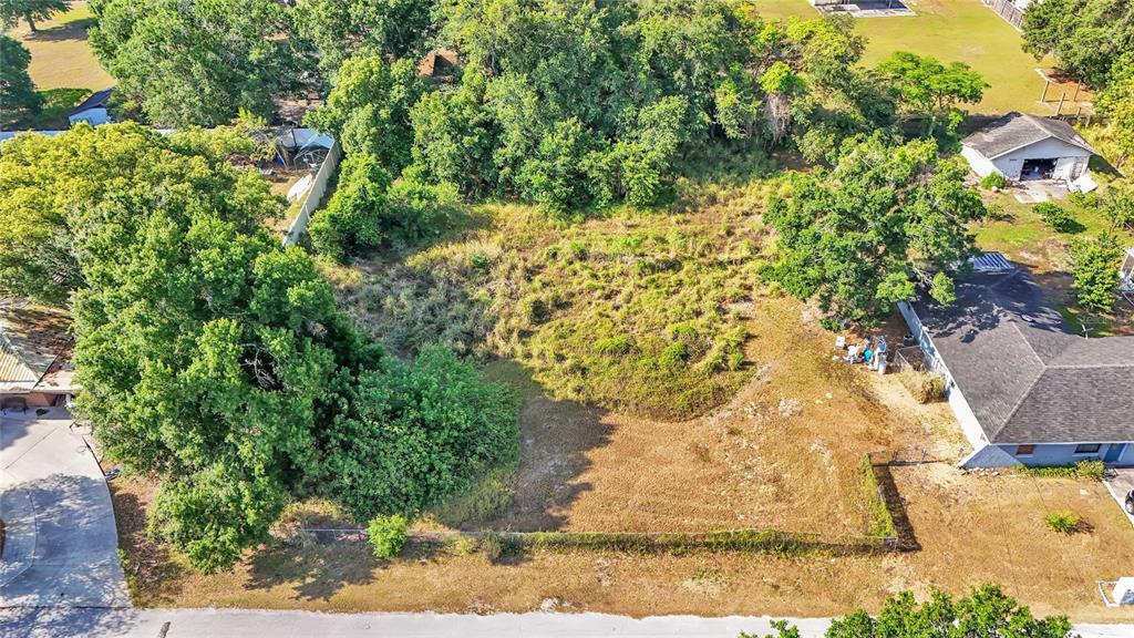 An aerial view shows a vacant, fenced residential lot surrounded by trees and neighboring houses — 1405 POLSTON ROAD, EAGLE LAKE, FL