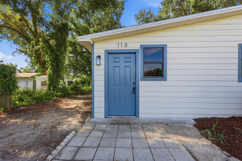 A blue front door with the number 118 above it on a light-colored siding exterior — 118 COURT STREET, KISSIMMEE, FL