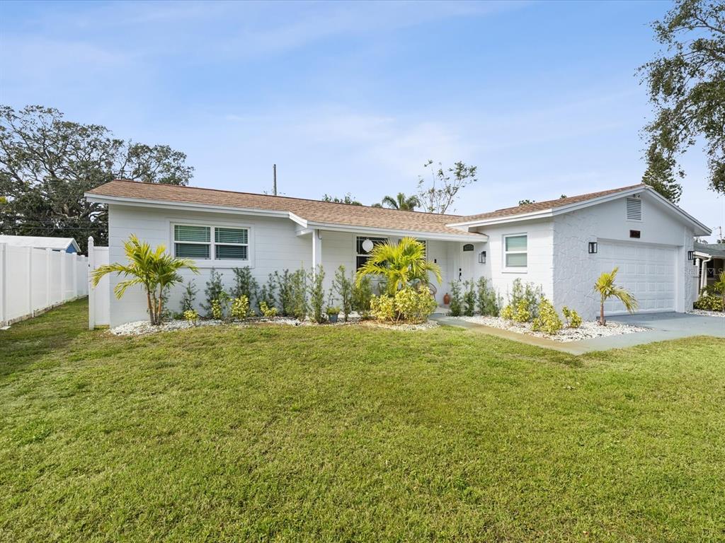 A single-story white house with a garage, a front lawn, and landscaping under a blue sky — 10264 OAKHURST ROAD, LARGO, FL