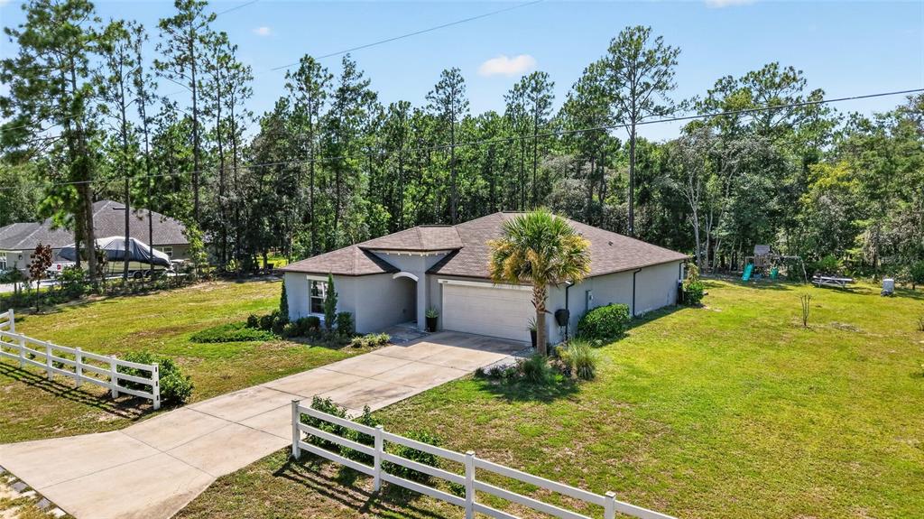 An aerial view shows a single-story house with a concrete driveway and white picket fence — 5684 SW 136TH AVENUE, OCALA, FL