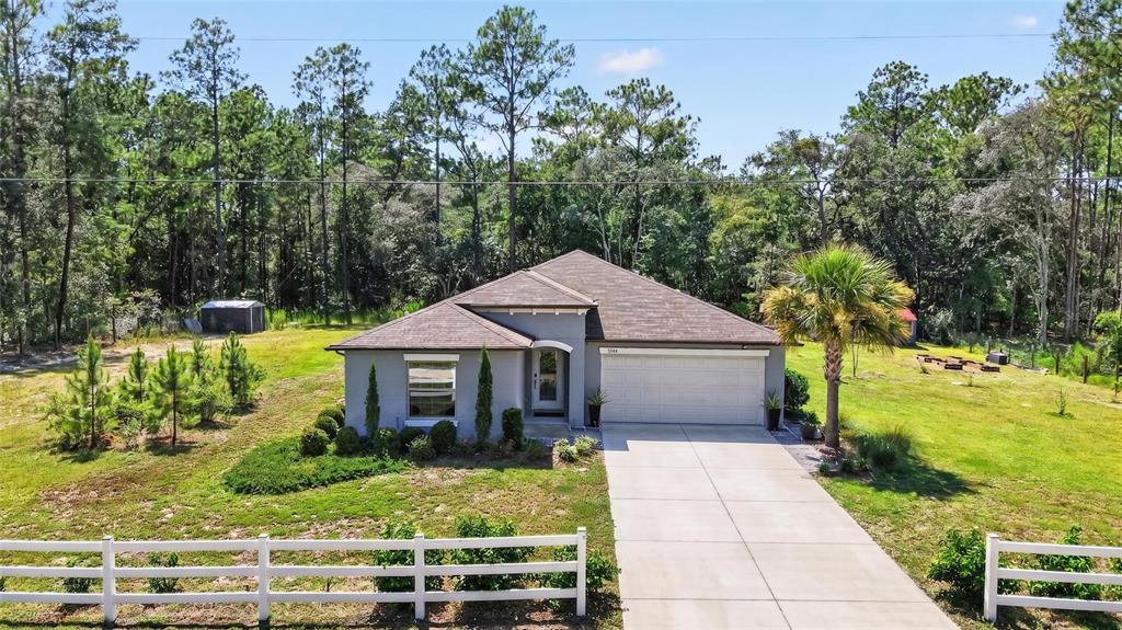 A single-story house with a two-car garage sits on a grassy lot with trees — 5684 SW 136TH AVENUE, OCALA, FL