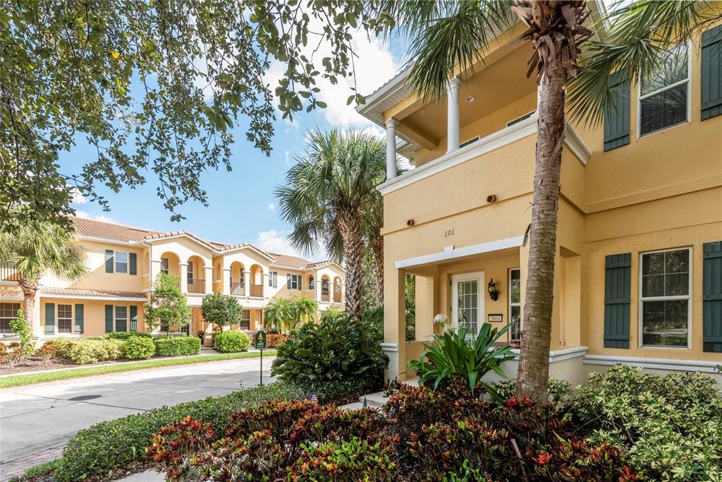 A two-story yellow stucco apartment building with dark shutters and a palm tree in front — 3860 82ND AVENUE CIRCLE E UNIT 101, SARASOTA, FL