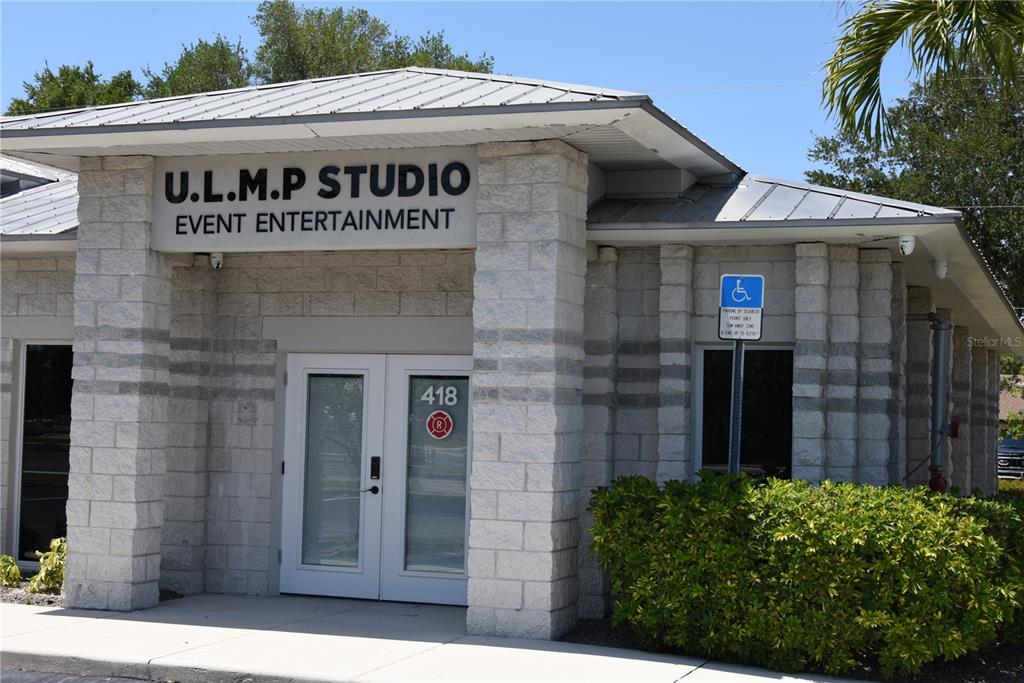 The exterior of a commercial building features a stone facade, double glass doors, and metal roofing — 418 S TAMIAMI TRAIL UNIT E3, OSPREY, FL