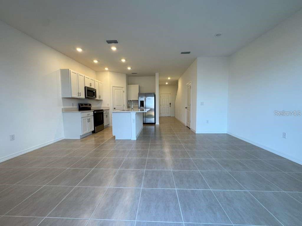 A kitchen with white cabinets, stainless steel appliances, and a central island on tiled flooring — 7629 WATERSCAPE DRIVE, GROVELAND, FL