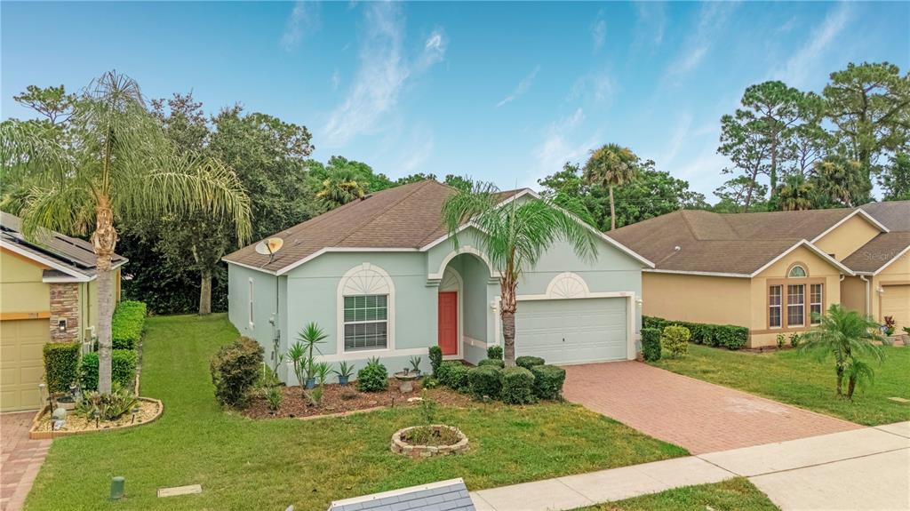 A light green single-story house with a red front door and a brick paver driveway — 3923 SUNSET COVE DRIVE, PORT ORANGE, FL