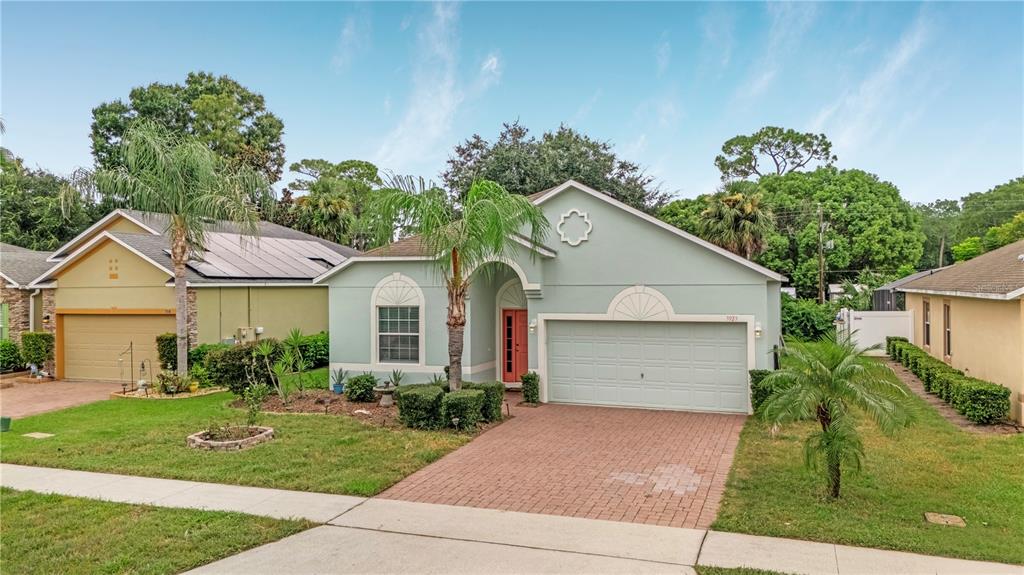 A light green single-story house features a brick driveway, a two-car garage, and palm trees — 3923 SUNSET COVE DRIVE, PORT ORANGE, FL