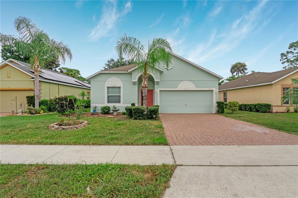 A light green single-story house with a brick driveway and a palm tree in front — 3923 SUNSET COVE DRIVE, PORT ORANGE, FL