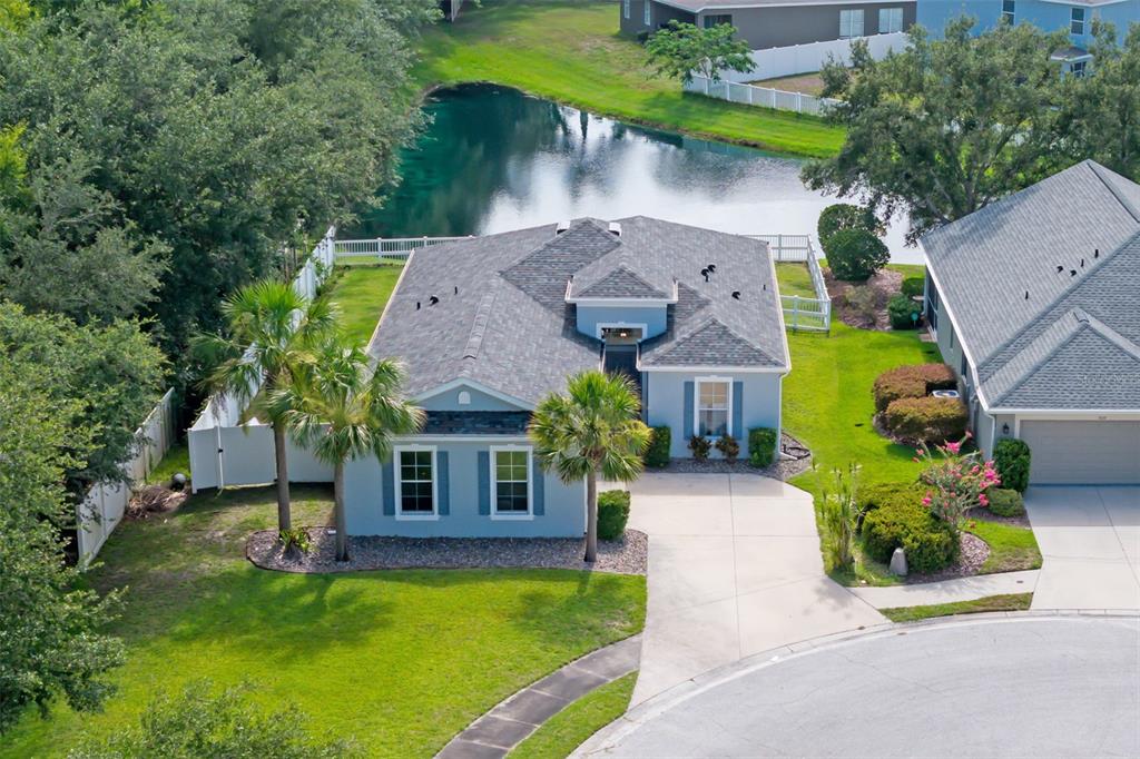 An aerial view of a blue single-story house with a gray roof and a backyard pond — 7005 56TH TERRACE E, PALMETTO, FL