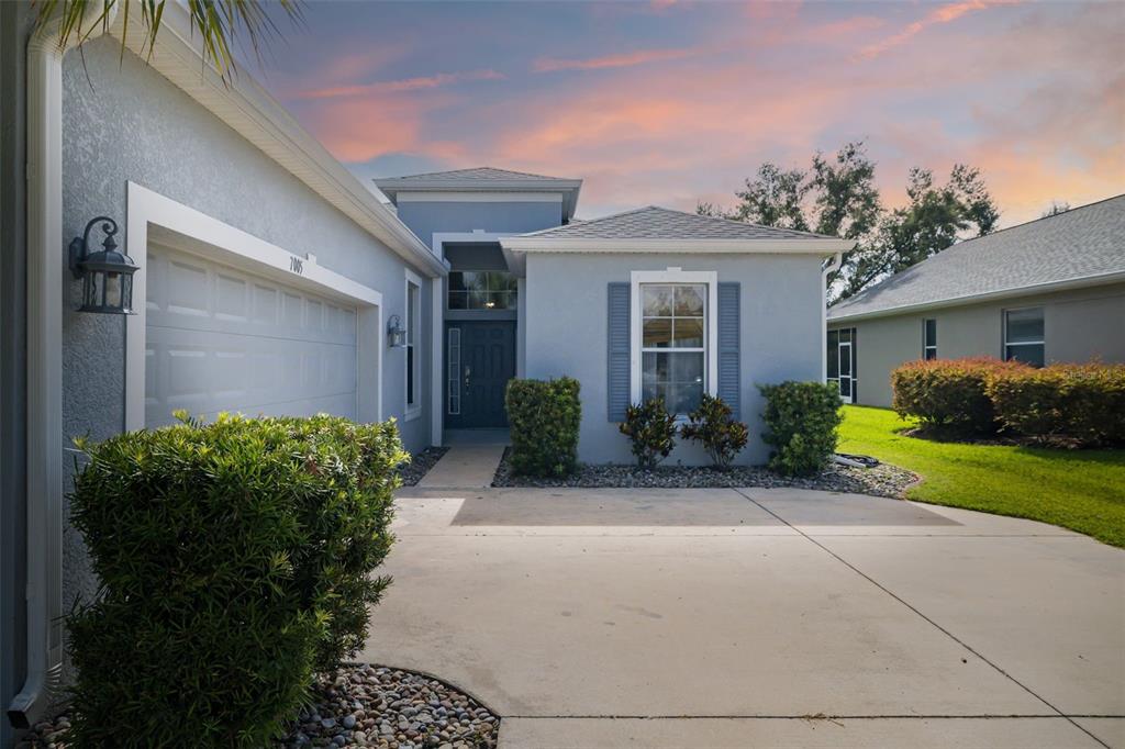 A light blue single-story house with a concrete driveway, garage, and front entrance — 7005 56TH TERRACE E, PALMETTO, FL