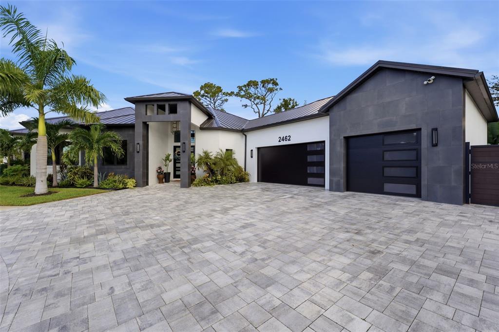 A modern single-story house with a paved driveway, dark stone accents, and a metal roof — 2462 MISSARA LANE, SARASOTA, FL