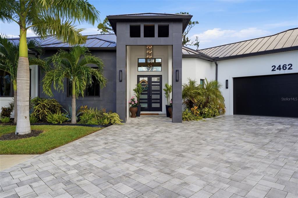 A modern house exterior features a dark gray entryway, a metal roof, and a paved driveway — 2462 MISSARA LANE, SARASOTA, FL