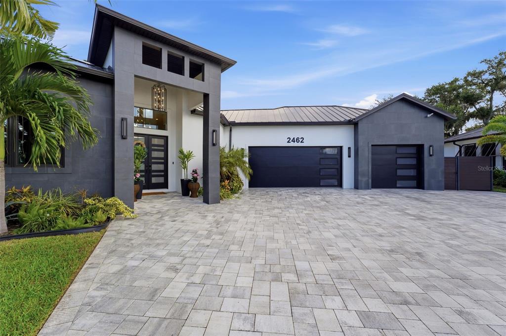A modern house exterior features dark gray stone siding, a paved driveway, and two garages — 2462 MISSARA LANE, SARASOTA, FL