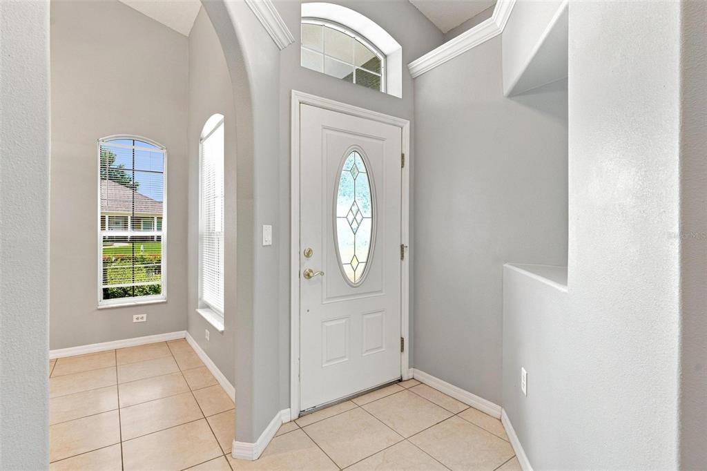 A gray house with a red front door and a concrete walkway leading to the entrance — 93 FAIRWAY CIRCLE, UMATILLA, FL