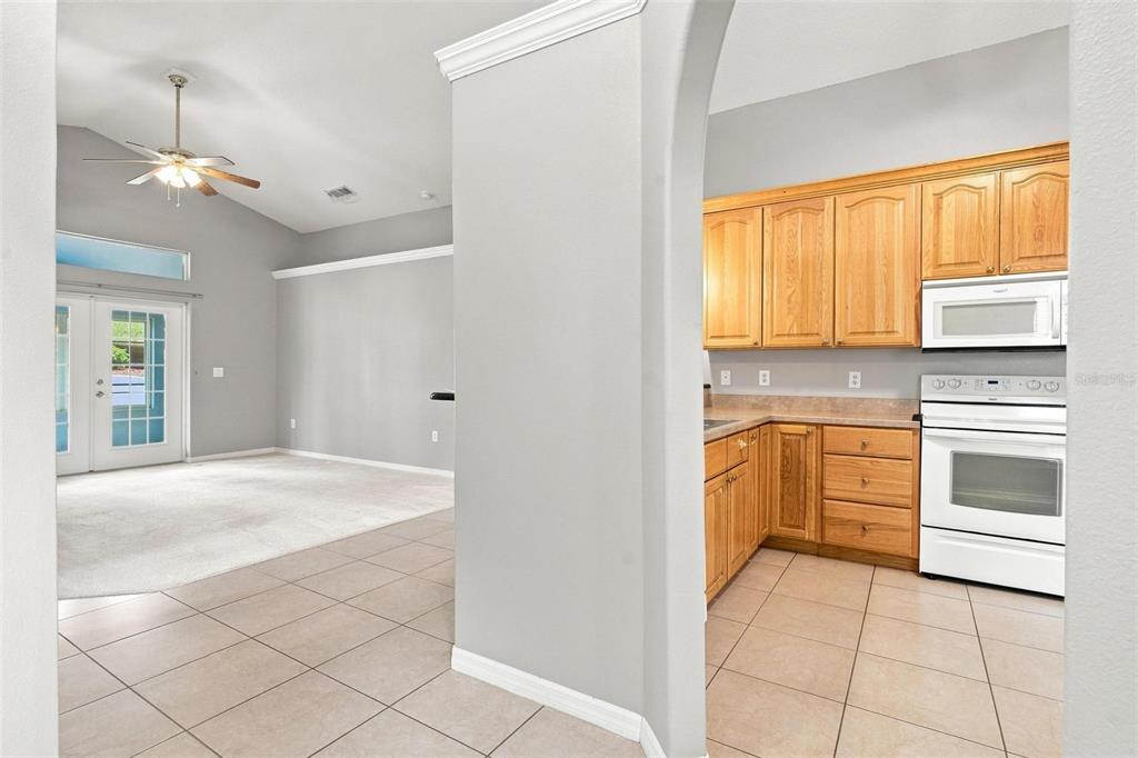 A gray house exterior features a red front door, an arched entryway, and landscaping — 93 FAIRWAY CIRCLE, UMATILLA, FL