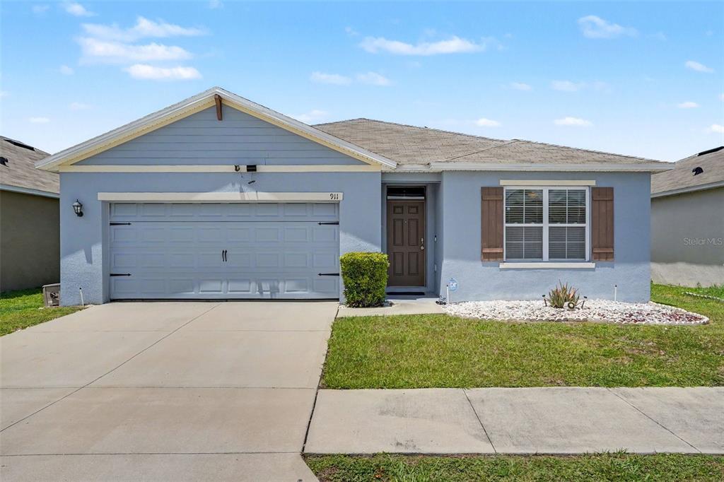 A light blue single-story house with a two-car garage and a concrete driveway — 911 WATERVILLE DR, AUBURNDALE, FL