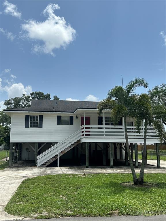 A white elevated house with a front porch, stairs, and a palm tree in the yard — 12055 MURRAY AVENUE, LARGO, FL
