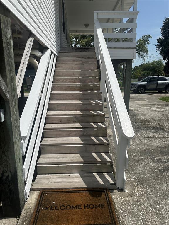 A set of wooden stairs leads up to the elevated porch of a white house — 12055 MURRAY AVENUE, LARGO, FL