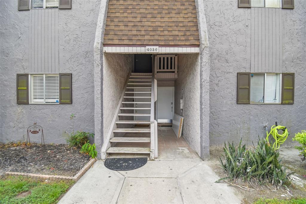 An exterior view of a multi-story building entrance with stairs leading to an upper unit — 4036 CORTEZ DRIVE UNIT A, TAMPA, FL