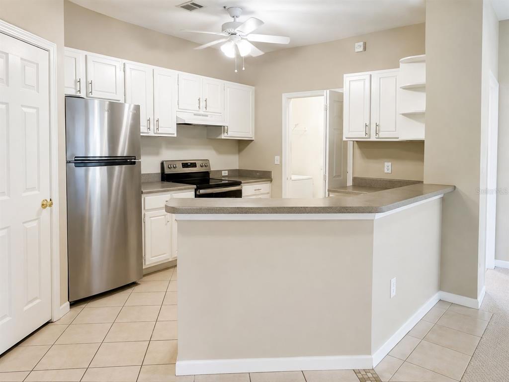 A kitchen with white cabinets, stainless steel appliances, a breakfast bar, and tile flooring — 2603 MAITLAND CROSSING WAY UNIT 101, ORLANDO, FL
