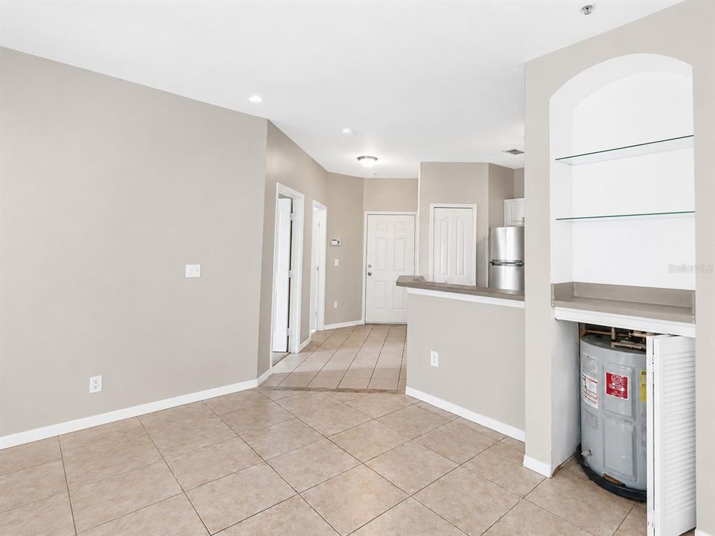 A room with tile flooring, a kitchen pass-through, and an exposed water heater in a closet — 2603 MAITLAND CROSSING WAY UNIT 101, ORLANDO, FL