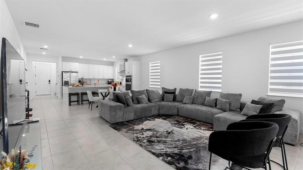 A spacious open-concept living room features a large grey sectional sofa and a modern kitchen — 4911 SHADY PINES DRIVE, ST CLOUD, FL