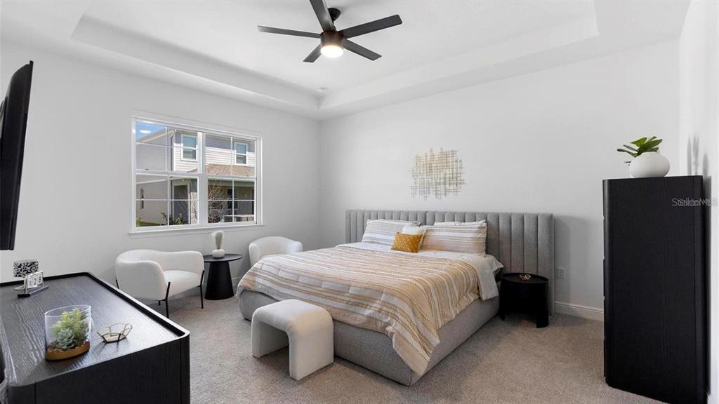 A bedroom features a gray upholstered bed, two white chairs, and a black dresser — 4911 SHADY PINES DRIVE, ST CLOUD, FL