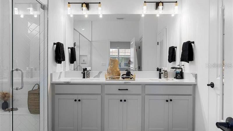 A modern bathroom features a double vanity with gray cabinets, a large mirror, and glass shower — 4911 SHADY PINES DRIVE, ST CLOUD, FL