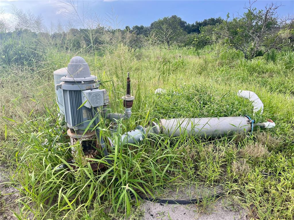 An outdoor electric water pump and irrigation piping system sit in a grassy field — HAYMAN ROAD, WAUCHULA, FL