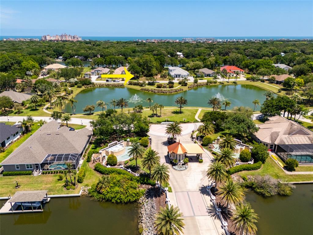 An aerial view shows a gated community entrance with a lake and several houses — 66 OLD OAK DRIVE S, PALM COAST, FL