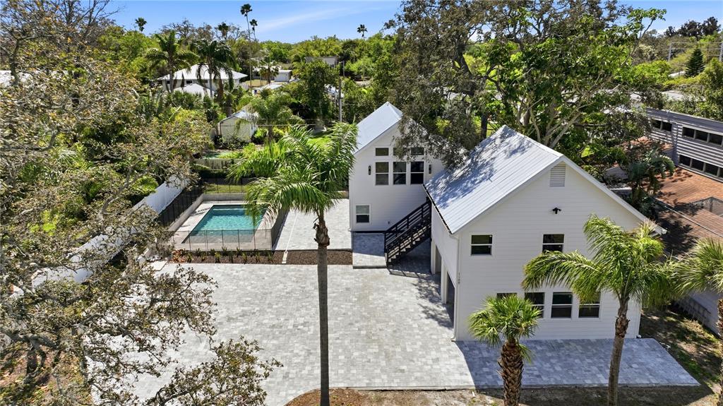 An exterior view of a white two-story house with a metal roof, pool, and garage — 1109 CHARLES STREET, CLEARWATER, FL