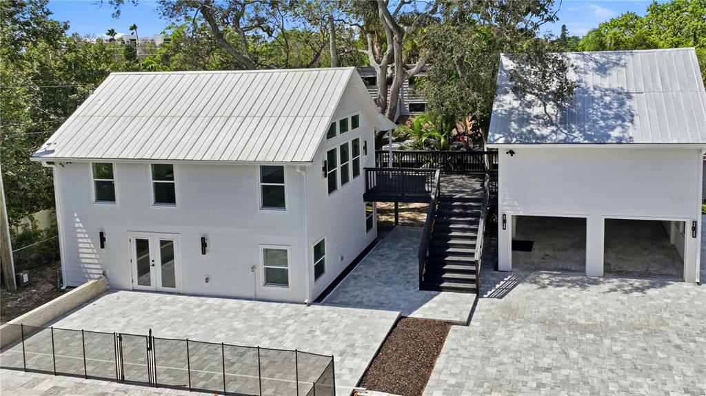 A white two-story house with a metal roof, pool, and detached garage at sunset — 1109 CHARLES STREET, CLEARWATER, FL