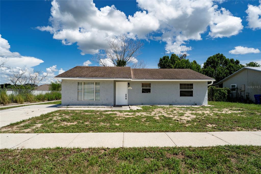 A single-story house with a gray stucco exterior, a brown roof, and a white door — 276 18TH STREET NE, WINTER HAVEN, FL