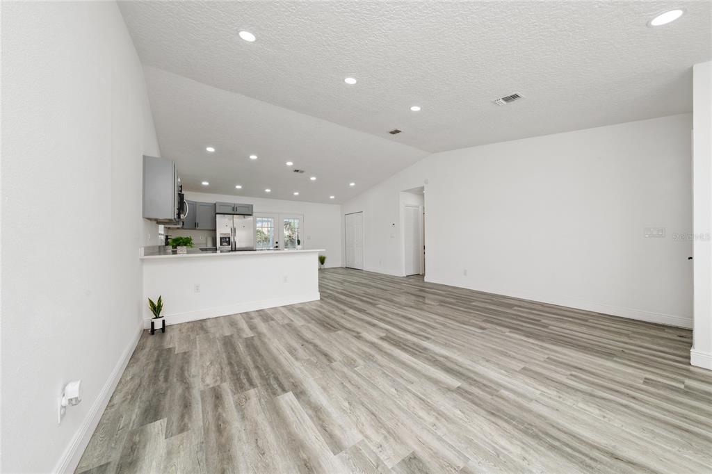 An open-concept living area features a kitchen with gray cabinets and light wood-look flooring — 276 18TH STREET NE, WINTER HAVEN, FL